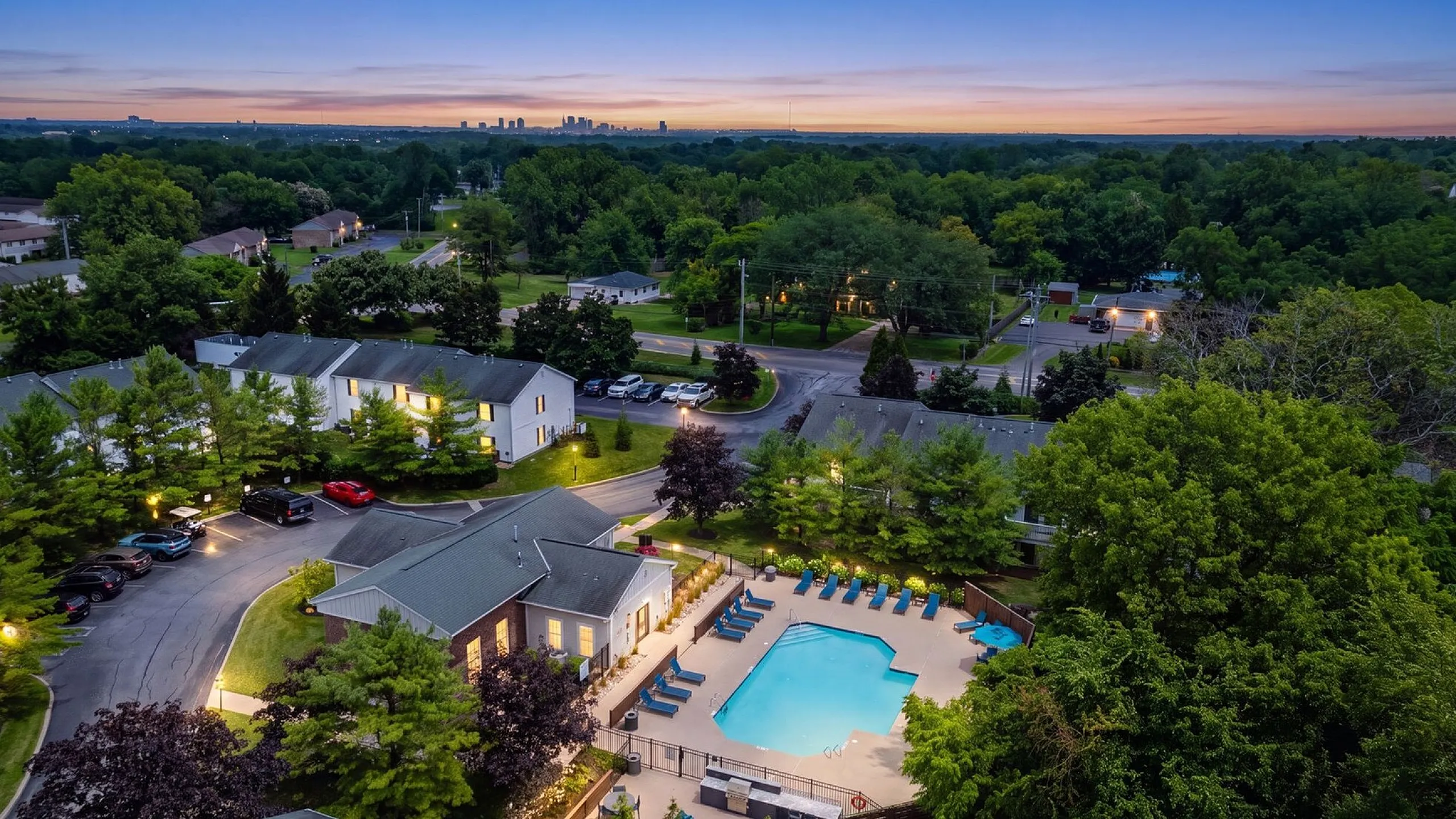 Scenic aerial view of a tranquil residential community with inviting pool surrounded by lush greenery, perfect for serene living.