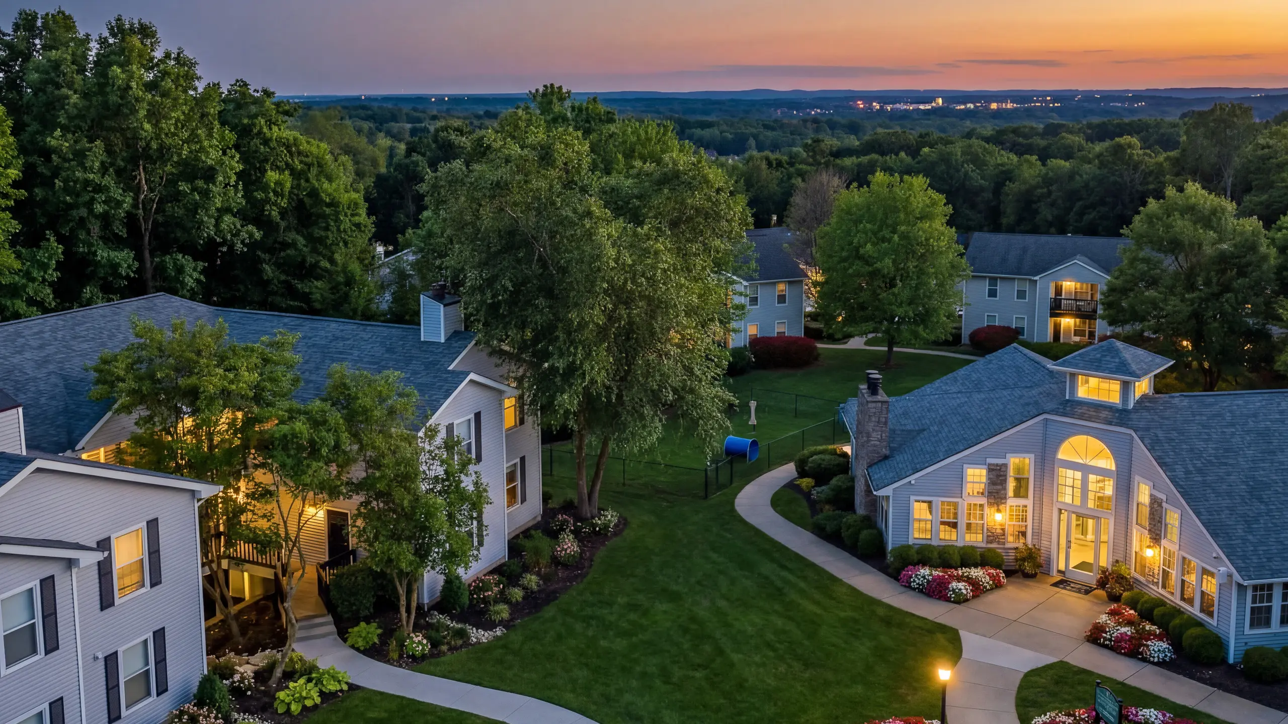 Charming sunset view of a lush apartment community with beautifully landscaped gardens and inviting pathways at The Retreat at Stillmeadow