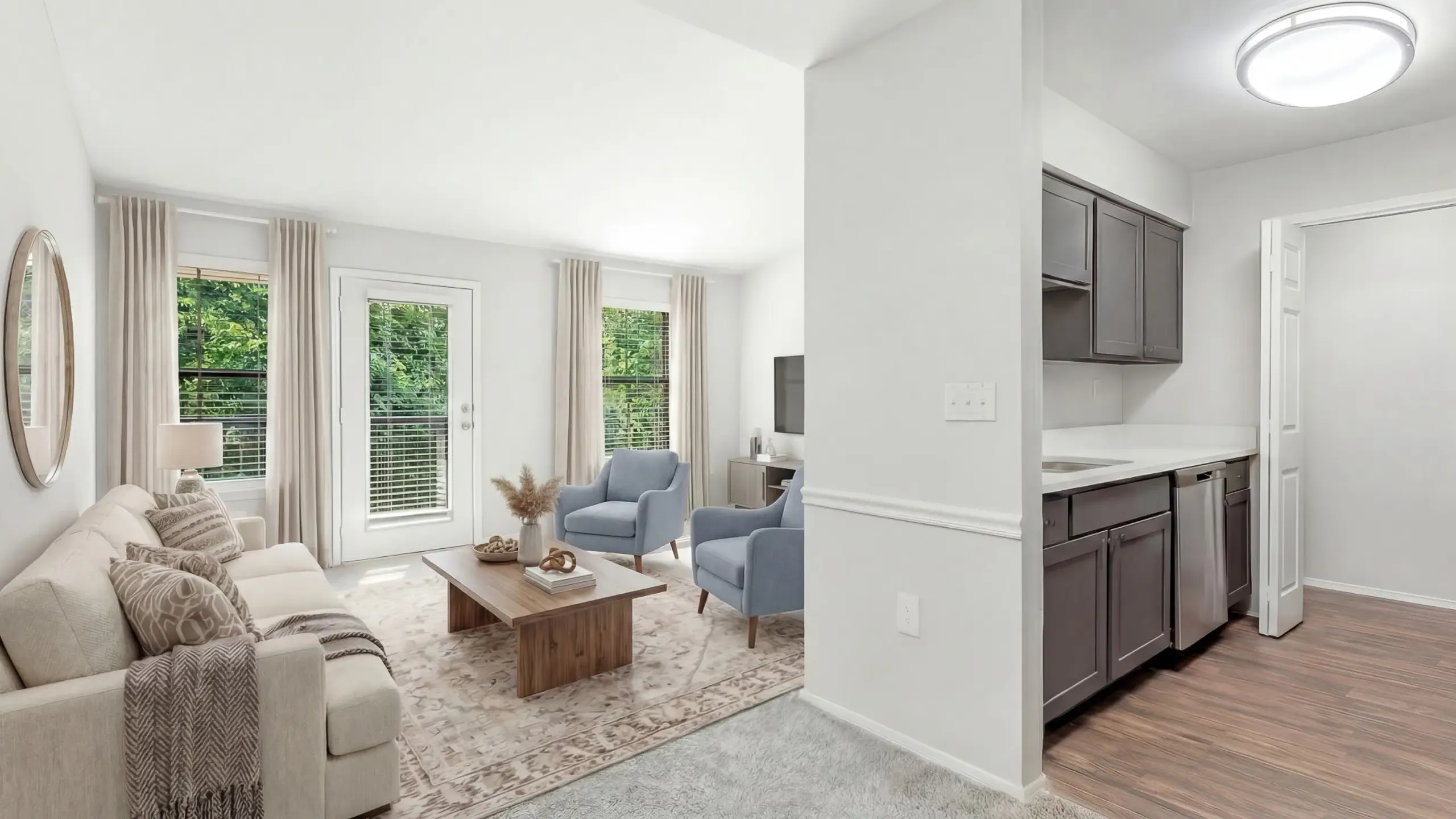 Bright and inviting living room with cozy decor, plush sectional sofa, modern dining area, abundant natural light through large windows, and elegant light fixtures at Timber Hollow Apartments