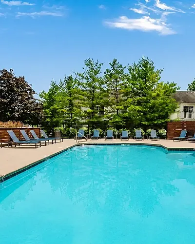 Inviting outdoor pool area with modern sun loungers and lush greenery, perfect for relaxation and leisure.