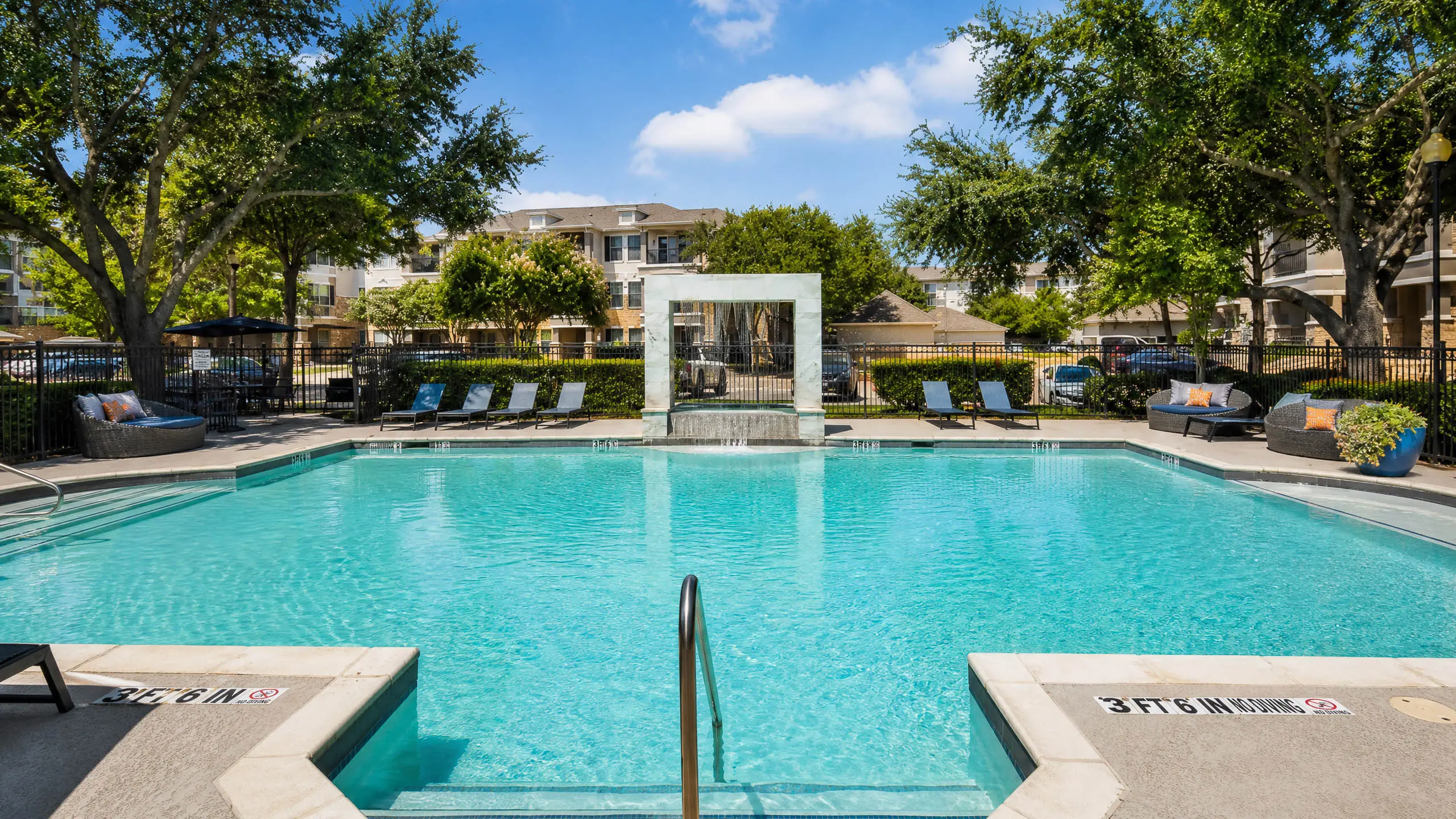 Inviting outdoor pool surrounded by lush greenery and modern lounge seating, perfect for relaxation and leisure.