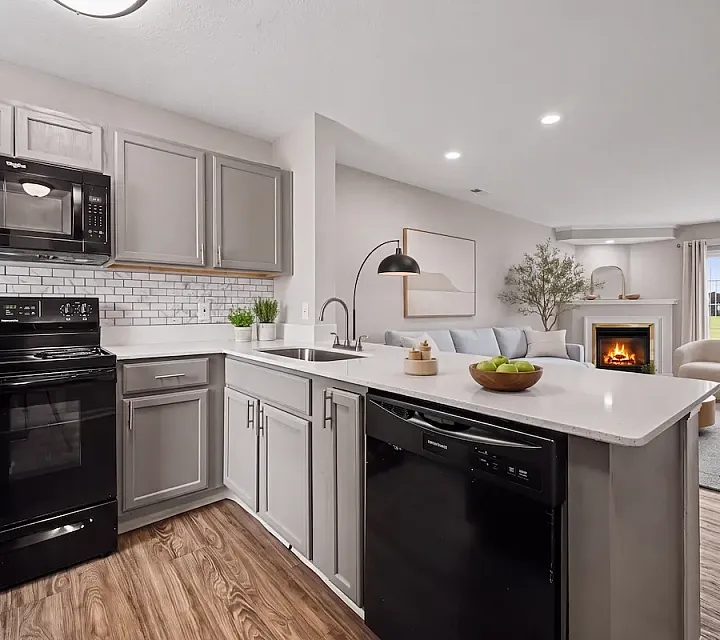 Chic open-concept kitchen and living area with elegant cabinetry, a cozy fireplace, and natural light pouring in through large windows at Alkire Glen Apartments.