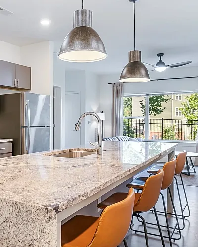 Bright and modern open-concept living space featuring a sleek kitchen with dark cabinetry, stylish dining area, and cozy living room with abundant natural light.