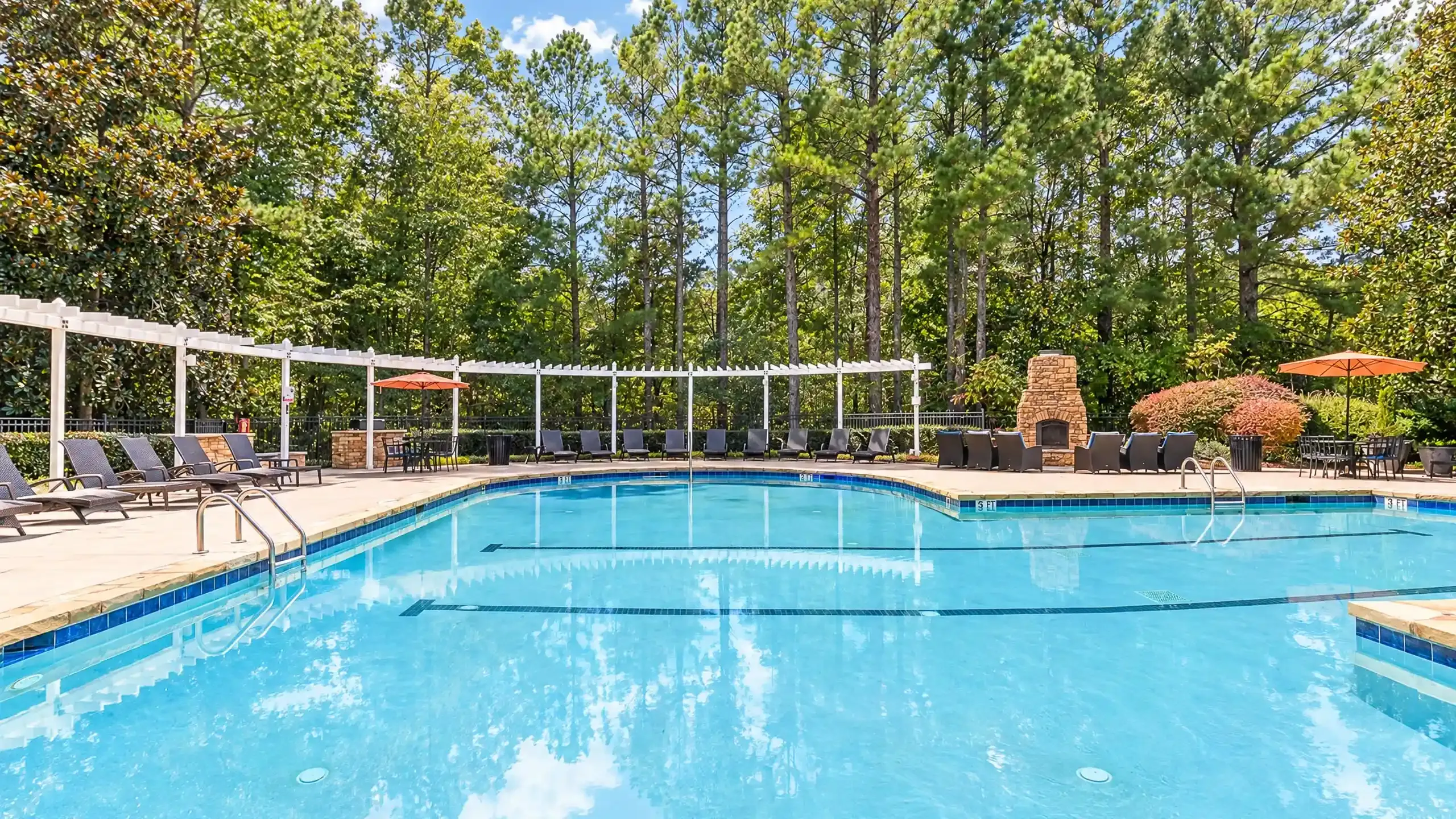 Inviting outdoor pool area with elegant lounge chairs and vibrant greenery, perfect for relaxation and leisure at Summer Park Apartments.