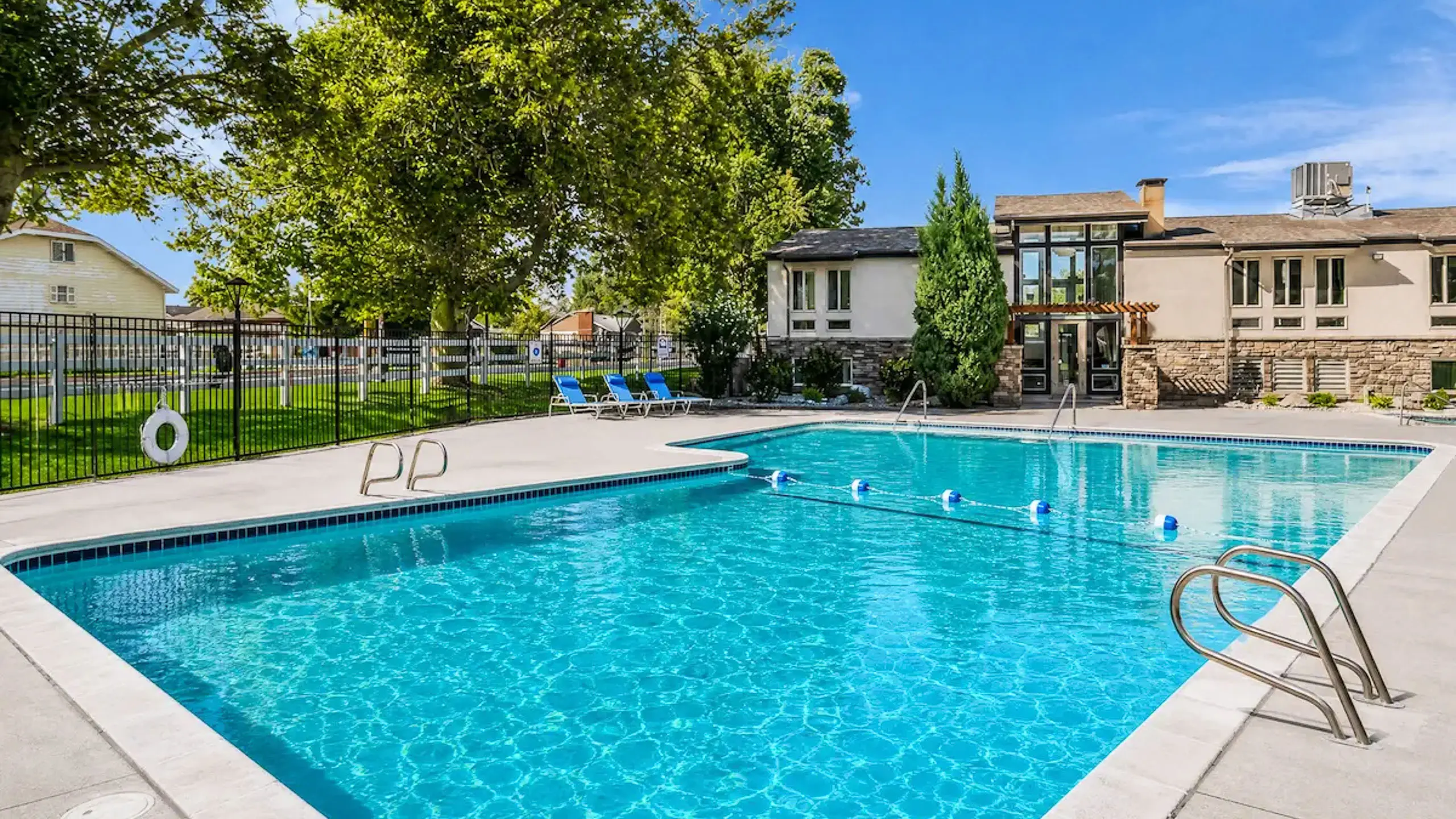 Charming outdoor pool area at Fox Point in Old Farm Apartments with sparkling water, surrounded by lush greenery and lounge seating.