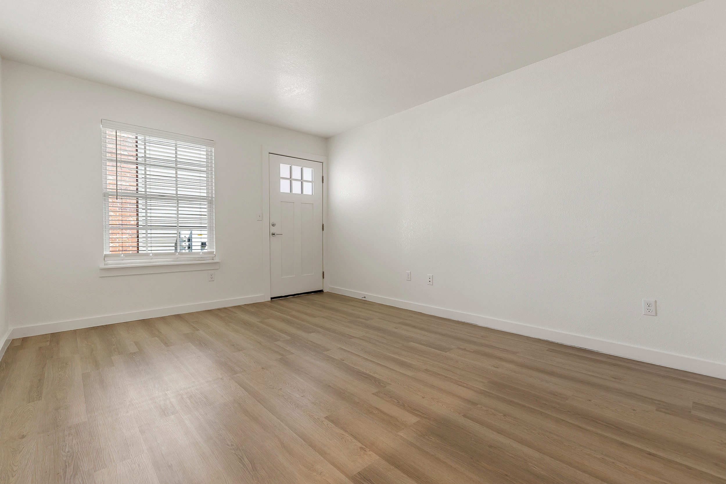 Bright and inviting living space with beautiful wood flooring and ample natural light from a large window.