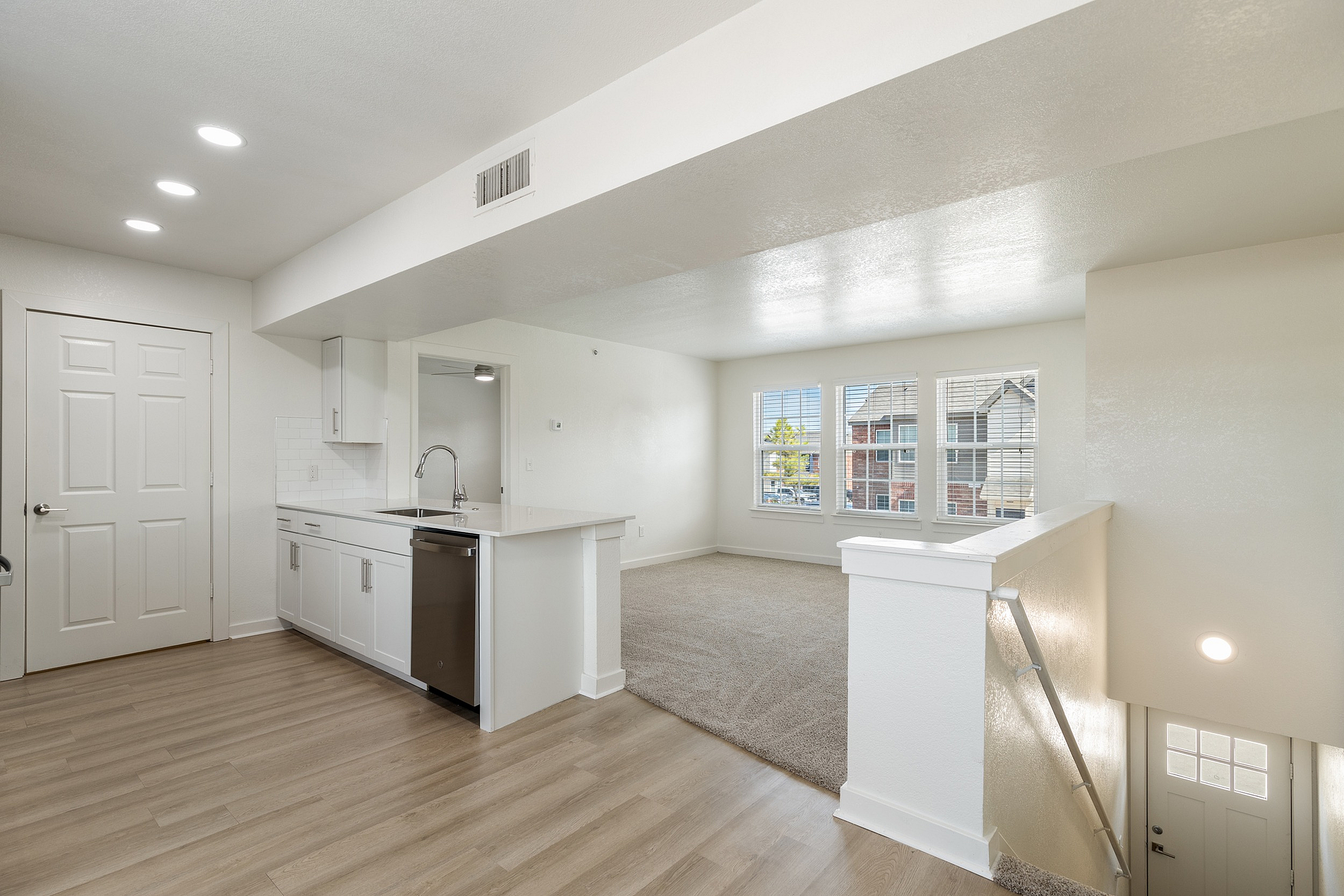 Bright and modern apartment interior featuring an open-concept kitchen with sleek cabinetry, hardwood floors, and a cozy living area with large windows offering inviting natural light.