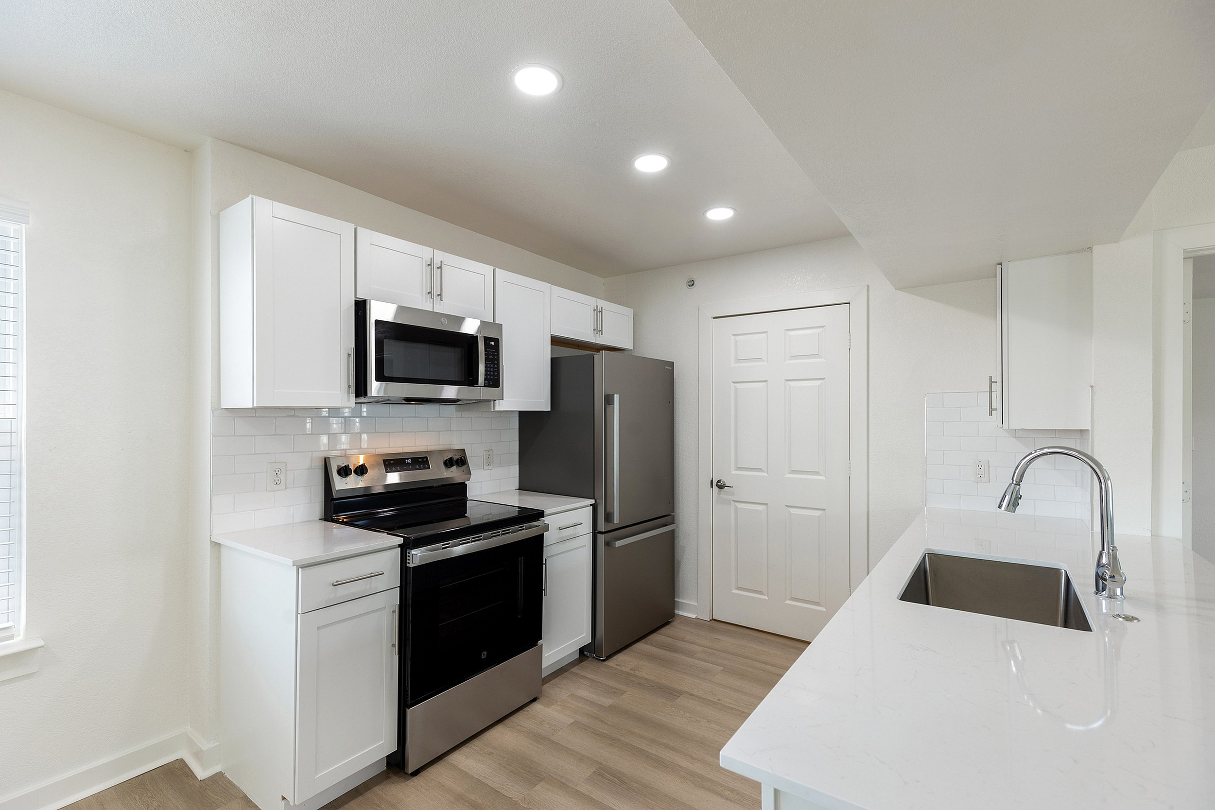 Modern kitchen with sleek white cabinets, stainless steel appliances, and elegant countertops under soft recessed lighting.
