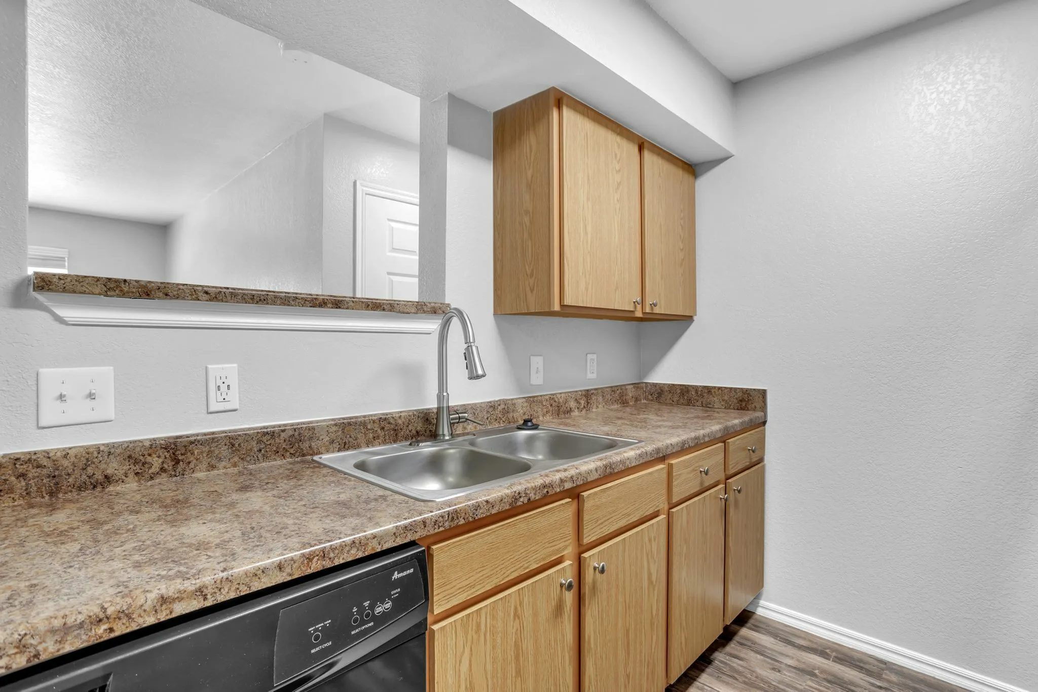 Modern kitchen with sleek countertops, double sink, and elegant wooden cabinetry, offering a spacious and functional design.
