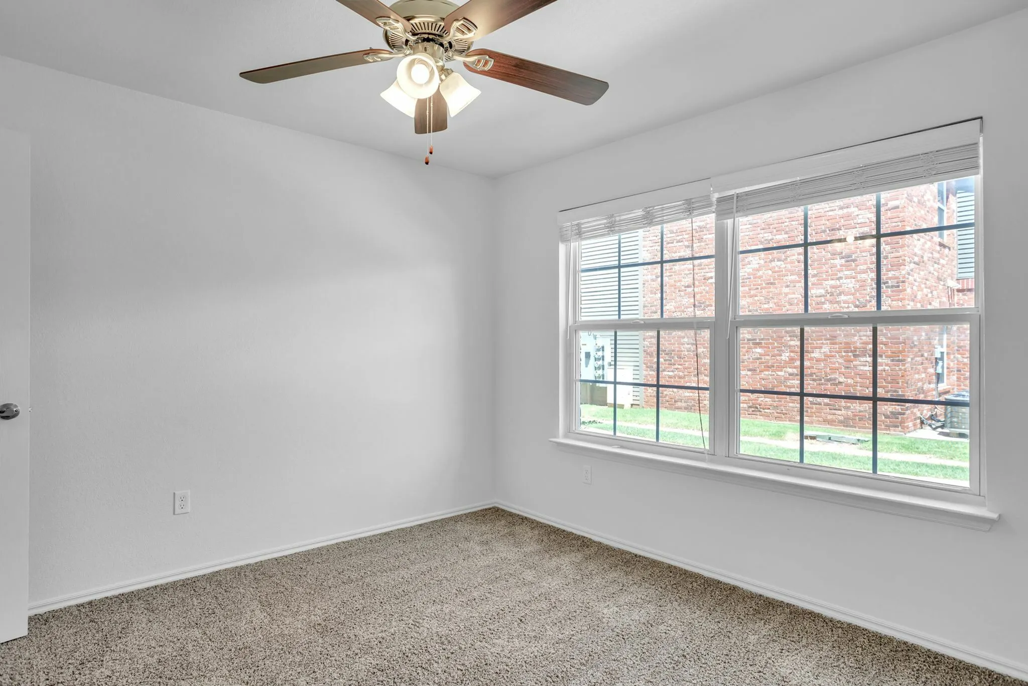Bright and cozy bedroom with plush carpeting, ceiling fan, and large window offering abundant natural light.