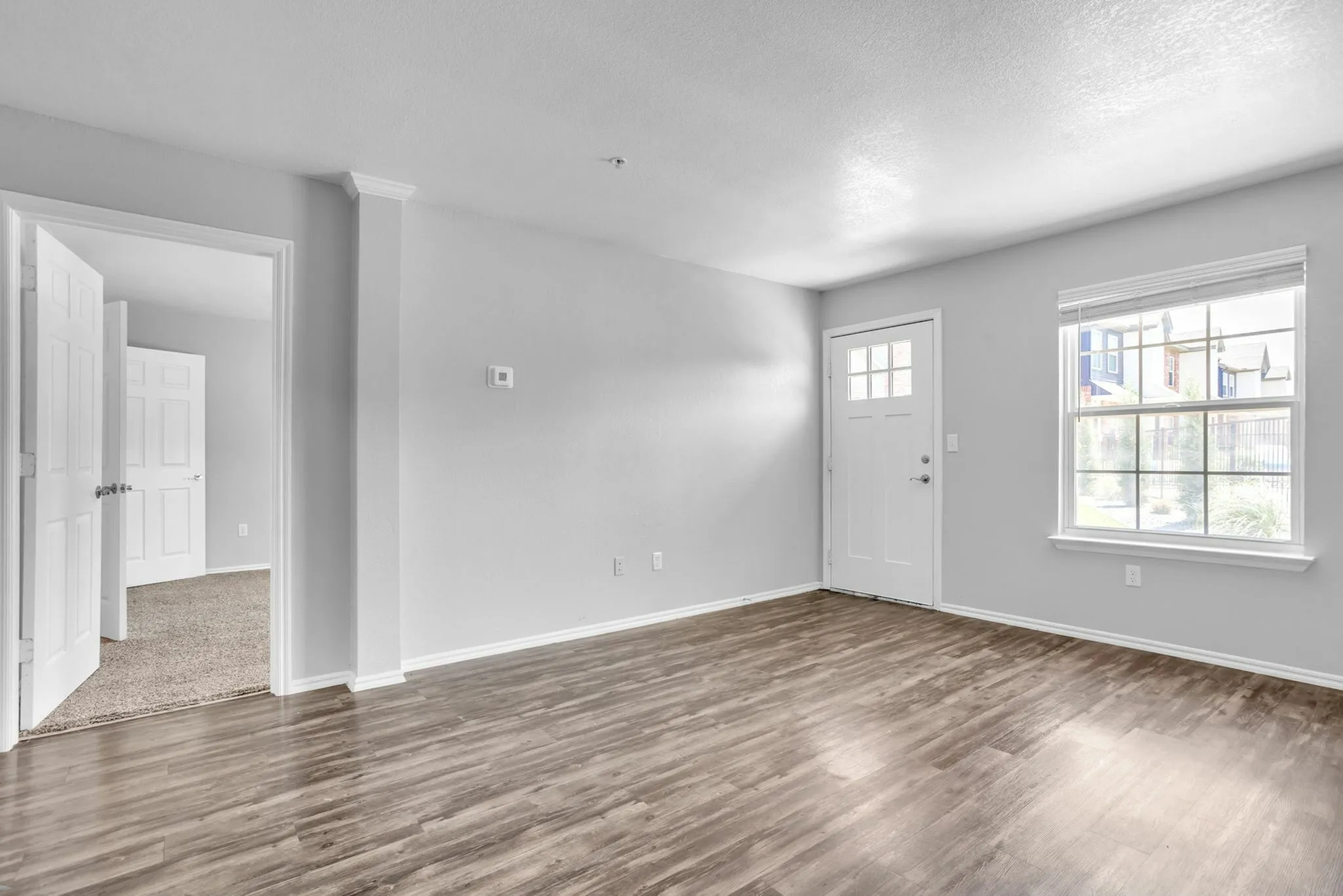 Bright and airy living space with elegant flooring and large window for natural light.