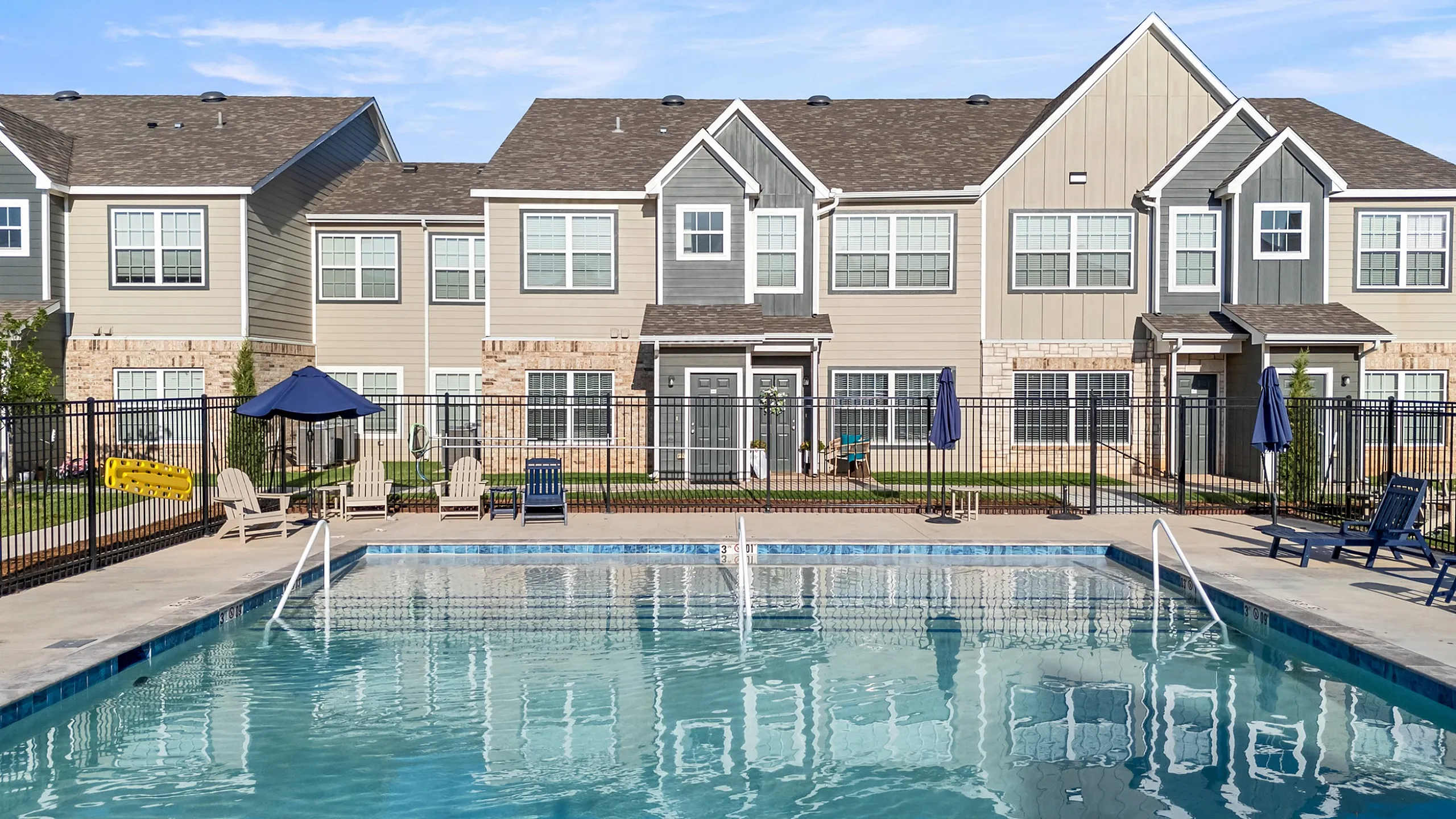 Inviting modern townhouse community featuring a sparkling swimming pool and cozy outdoor seating area for relaxation.