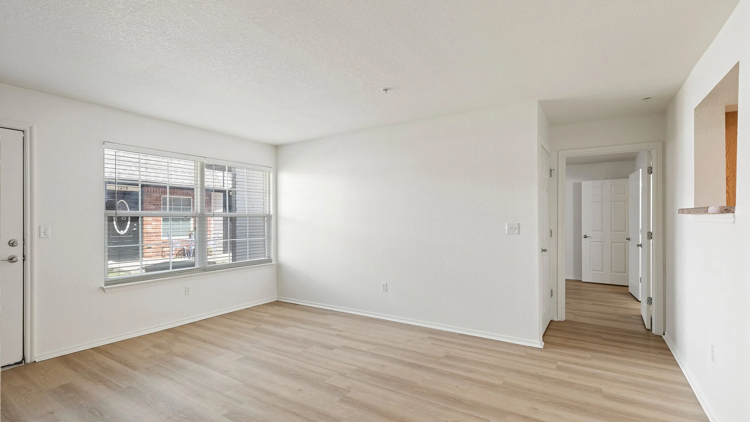 Bright, spacious apartment living area with large windows and elegant wood flooring, perfect for natural light lovers.