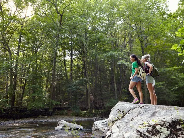 two friends hiking in the trees near a river together modera montville apartment homes for rent