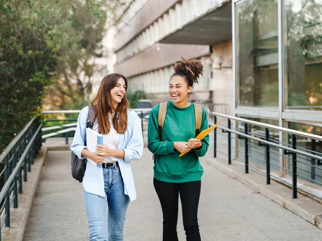 Two college students walking with book bags
