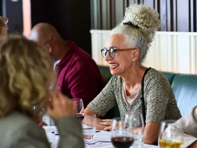 woman smiling at dinner table drinking wine modera st petersburg apartment homes for rent in florida