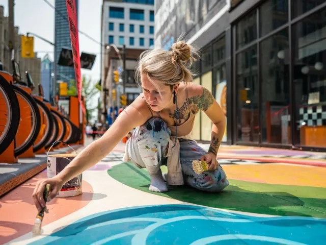 woman painting on sidewalk outside modera st petersburg apartment homes for rent in florida