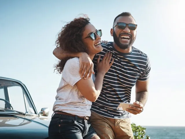 couple smiling with sunglasses on in front of car amavi kissimmee single family homes for rent in orlando fl