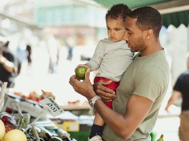 father and child buying fresh vegetables at farmers market modera falls church apartment homes for rent in va