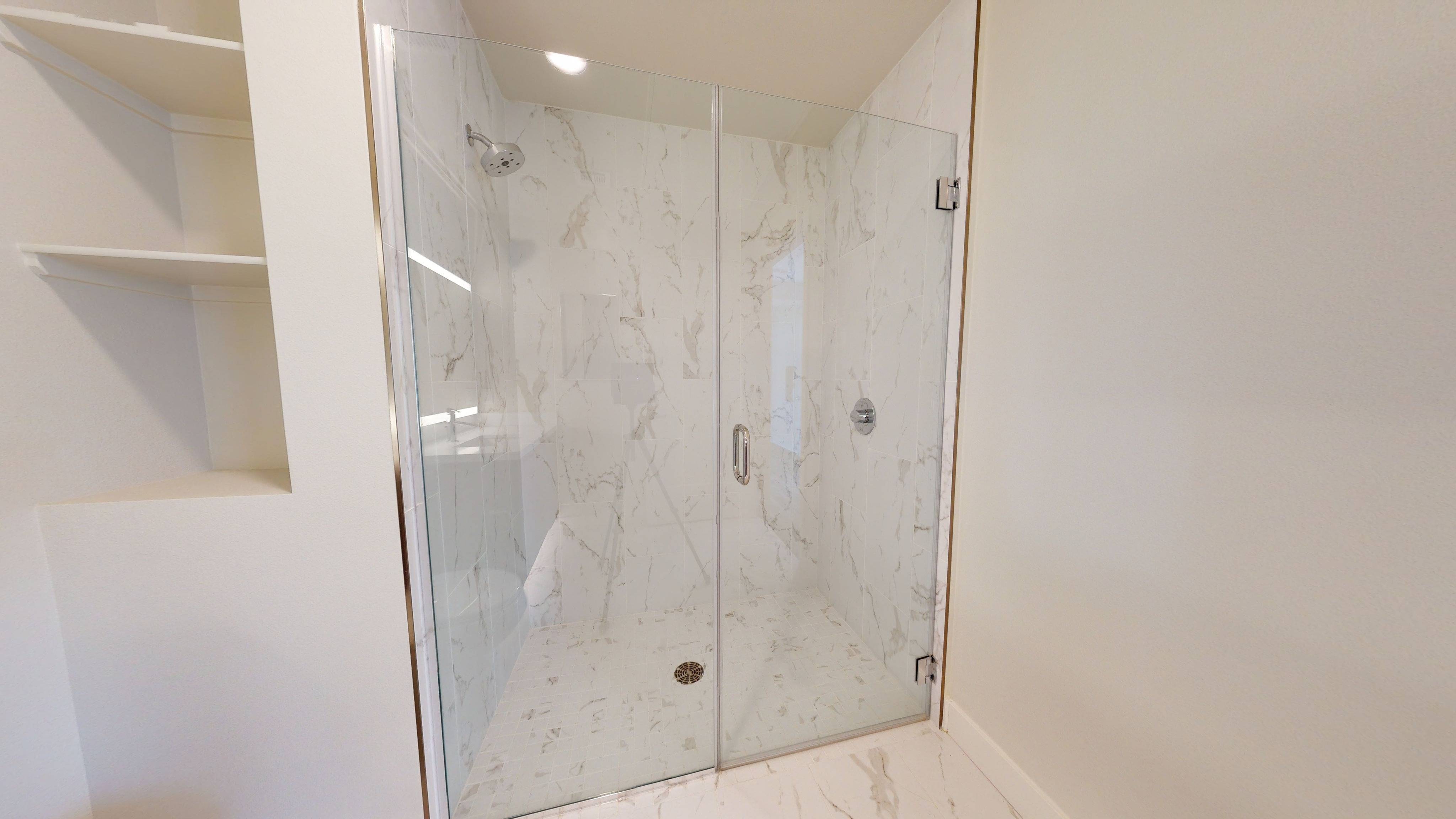 Glass enclosed showers with large tile surround*