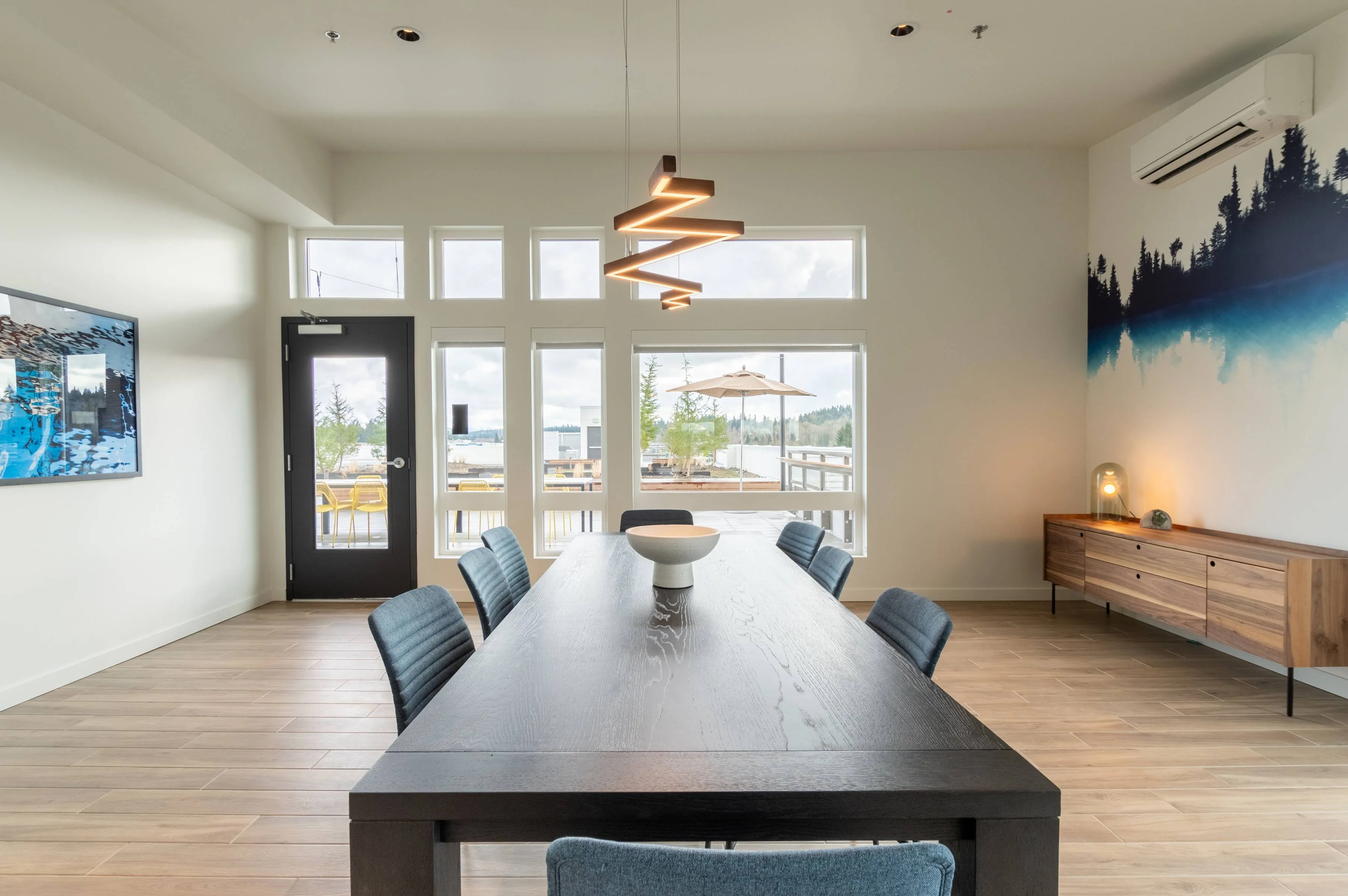Sky Lounge conference table with many chairs, view of rooftop and modern furniture, lighting, and mountain artwork