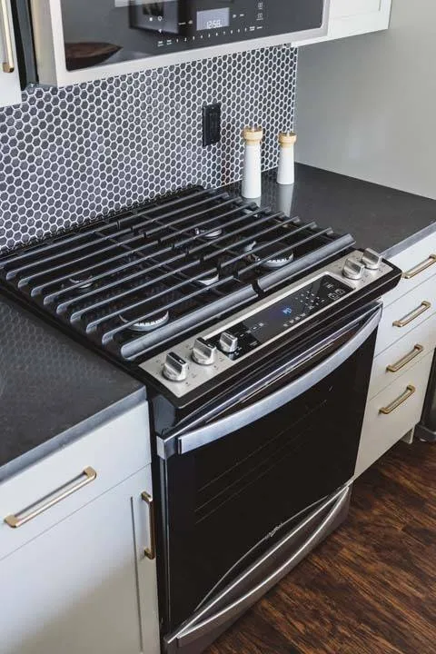 Gas range closeup with white cabinets and brass hardware