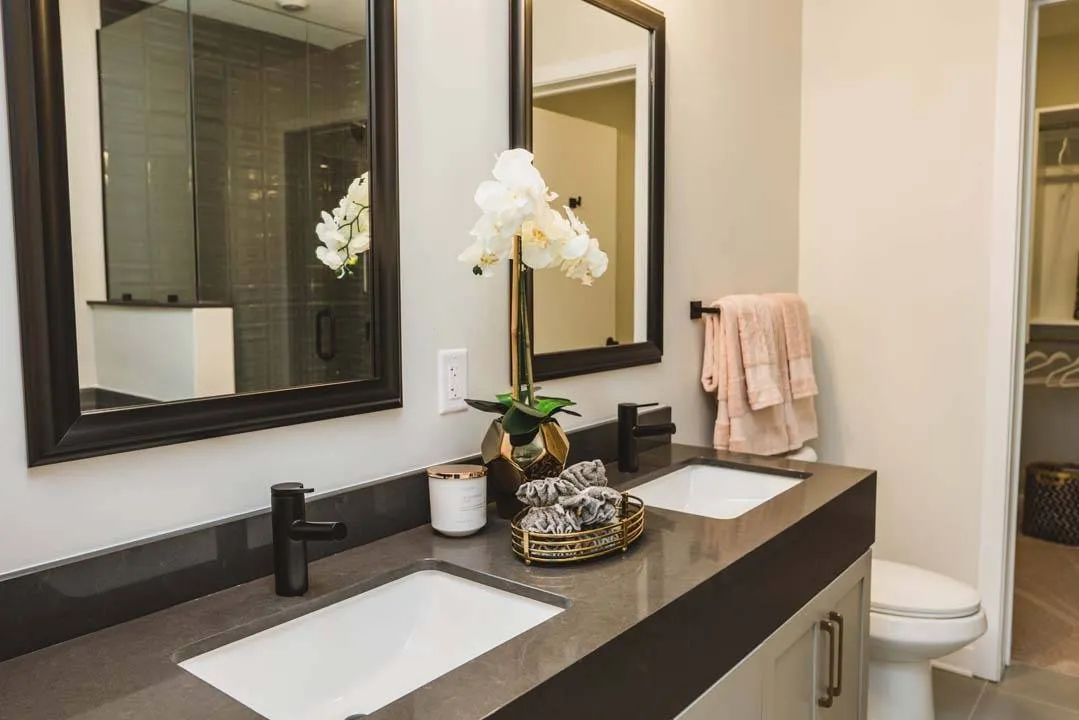 Elegant bathrooms with dark counters and white sinks with 2 mirrors and spacious closet