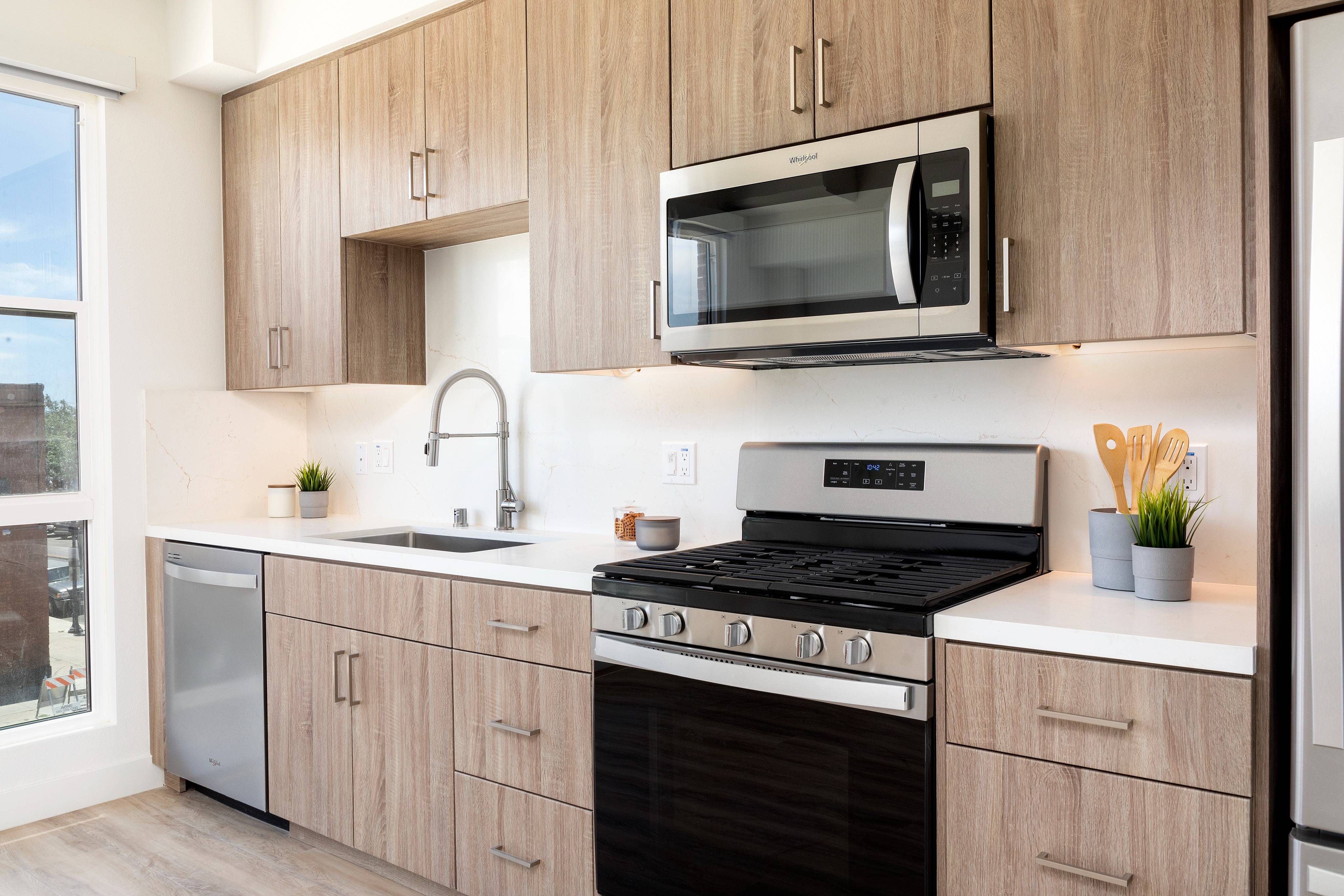Loft layout and modern kitchen with custom cabinetry, gas ranges and sleek hardware at Modera San Diego