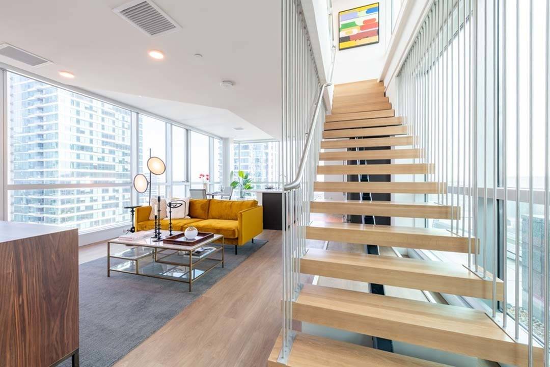 Glass-walled living room on 3 sides with stairs leading upstairs from living room