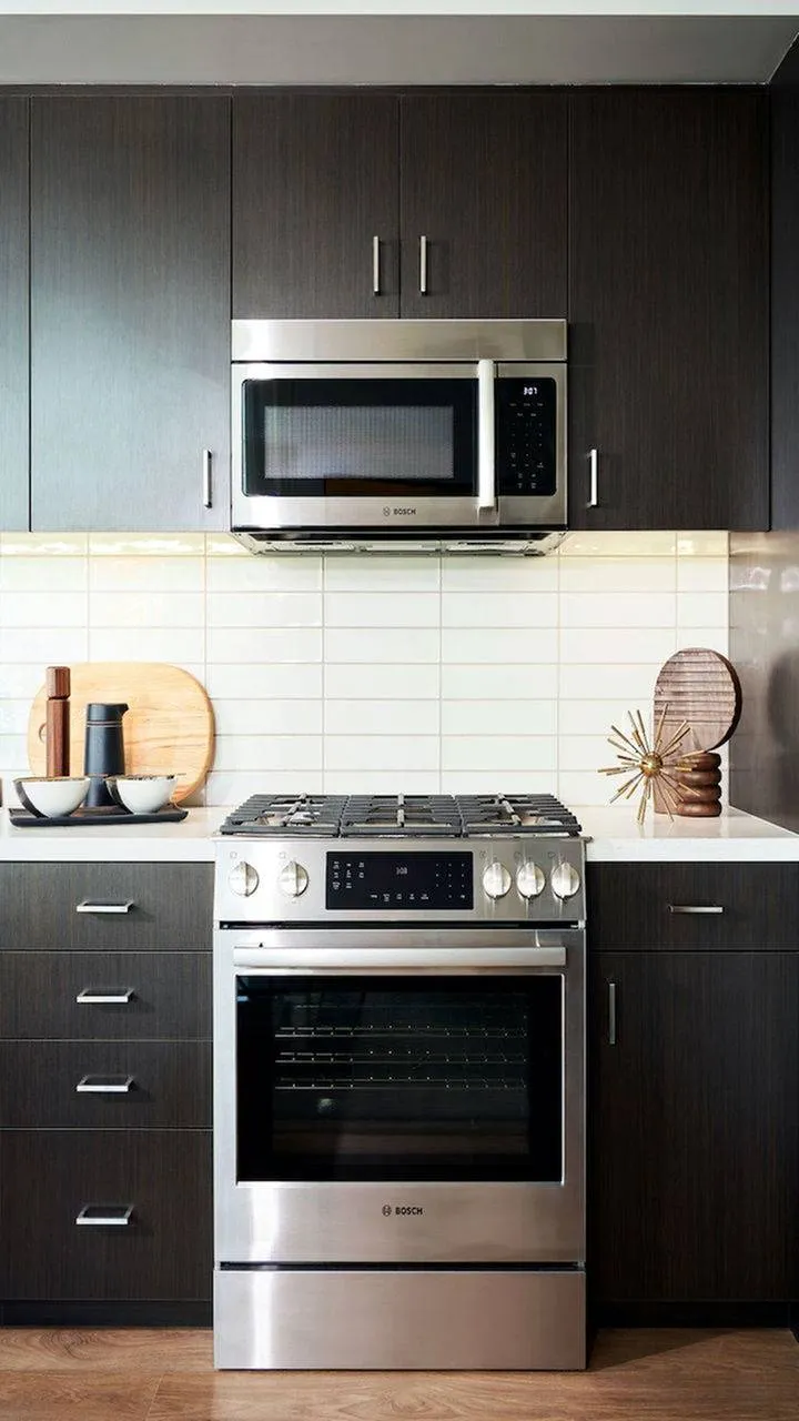 Gas stove in front of subway tile backsplash and dark cabinets