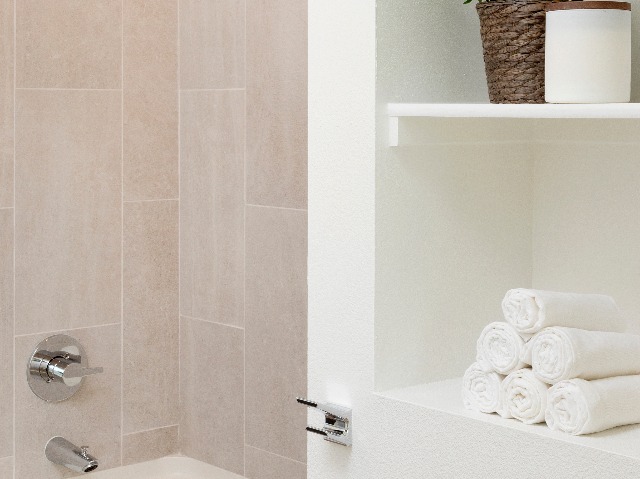 White soaking tub with beige tile surround and storage