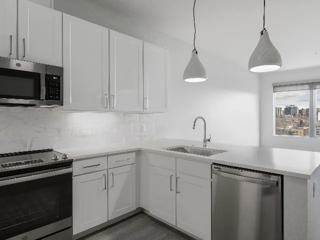 White gloss kitchen cabinets with white countertops and stainless steel appliances