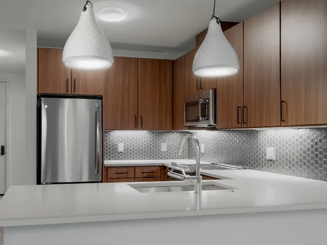 Close up of pendant lighting above kitchen island showing tile backsplash and kitchen sink
