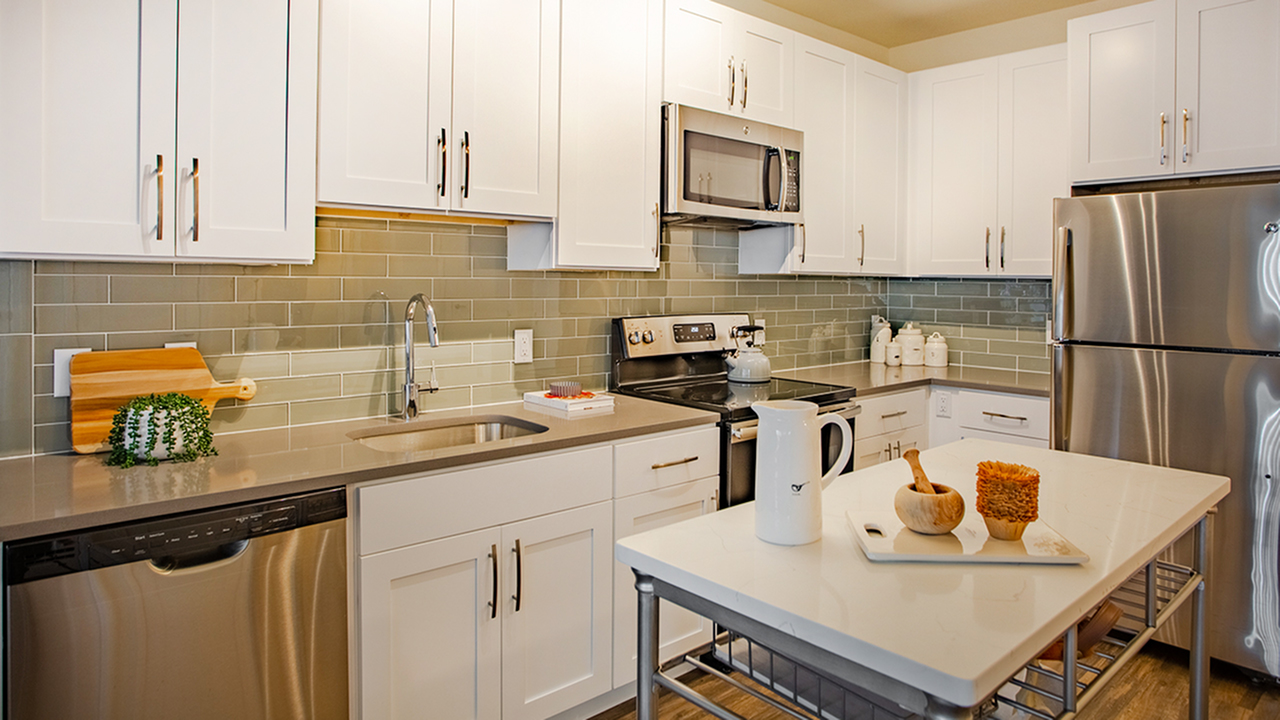 Kitchen featuring modern white cabinetry, stainless steel appliances and movable island