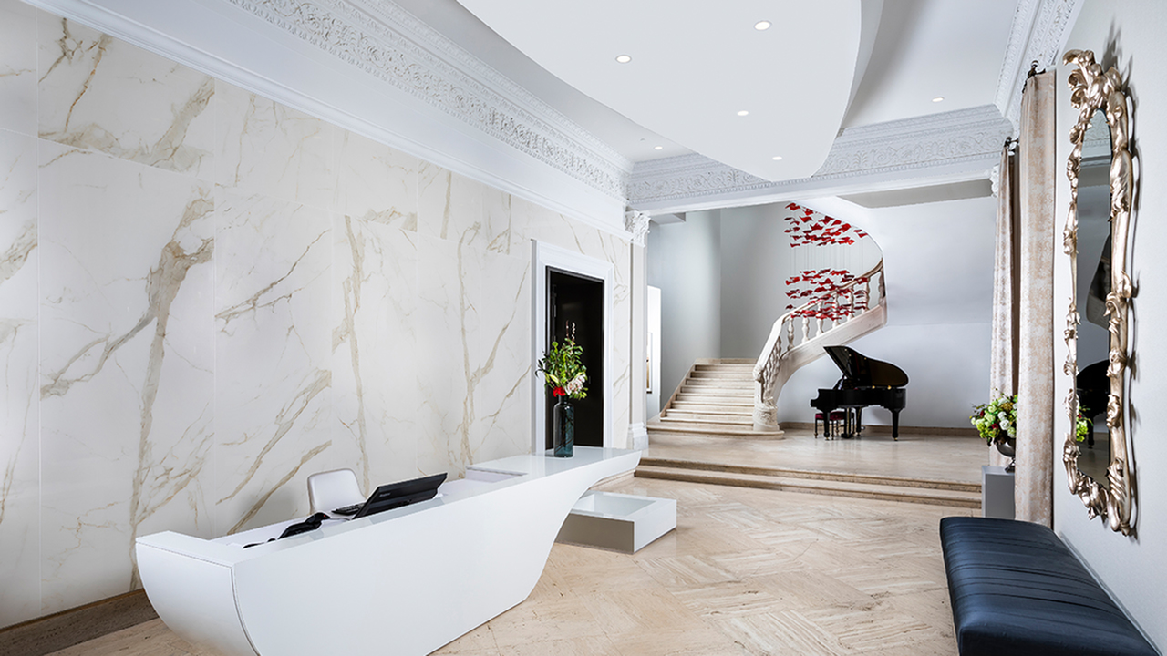 Main foyer with travertine flooring and marble wall behind concierge desk