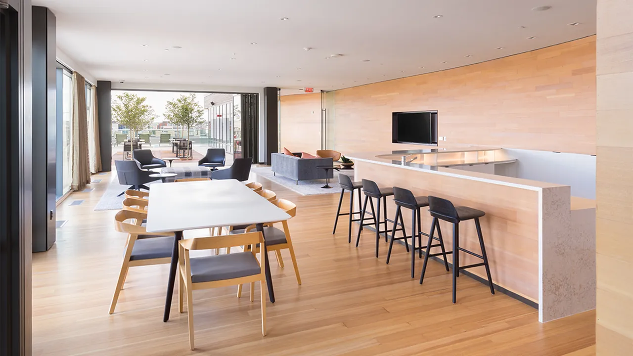 Roof clubroom featuring 80-inch TV lounge, kitchen, bar seating and communal dining table