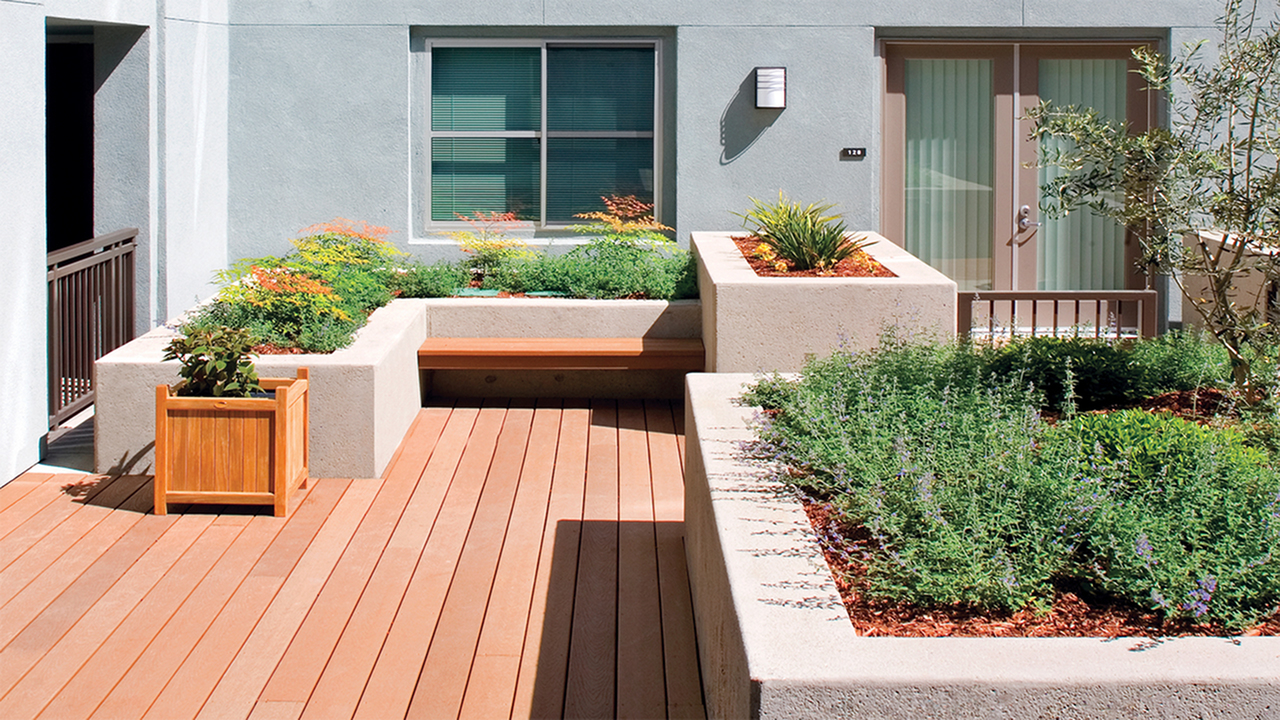Outdoor courtyard with wood decking and raised flower beds with seating