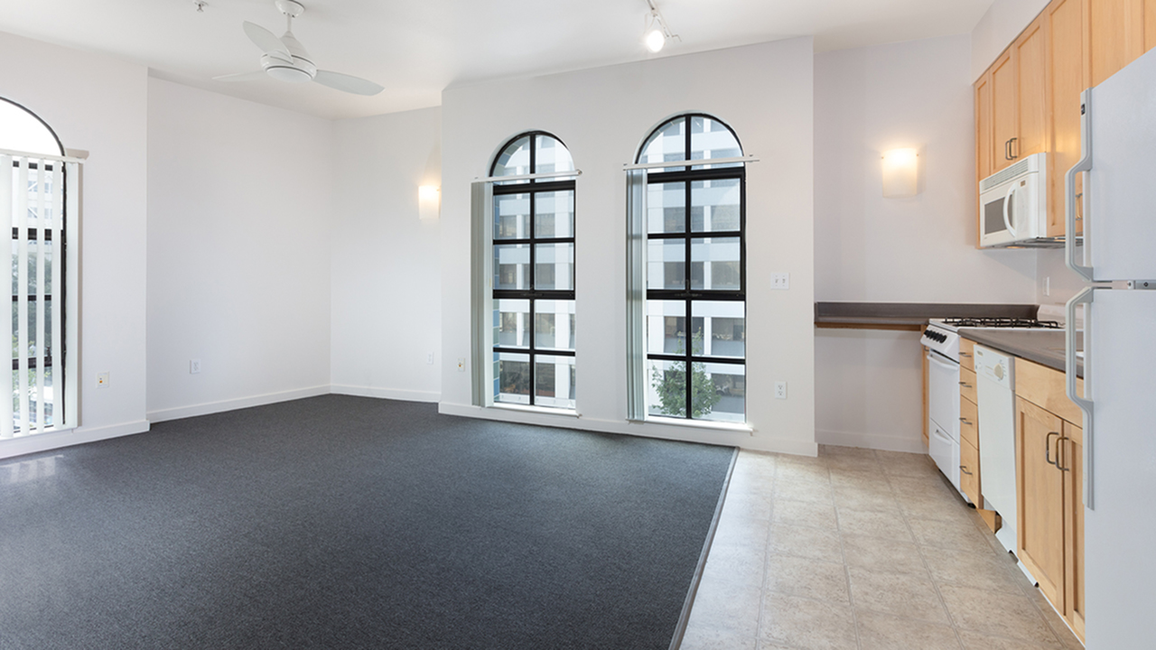 Living room and kitchen surrounded by over sized, arched windows