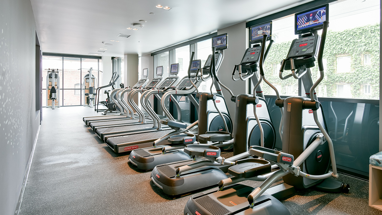 Fitness center with cardio equipment facing floor to ceiling windows