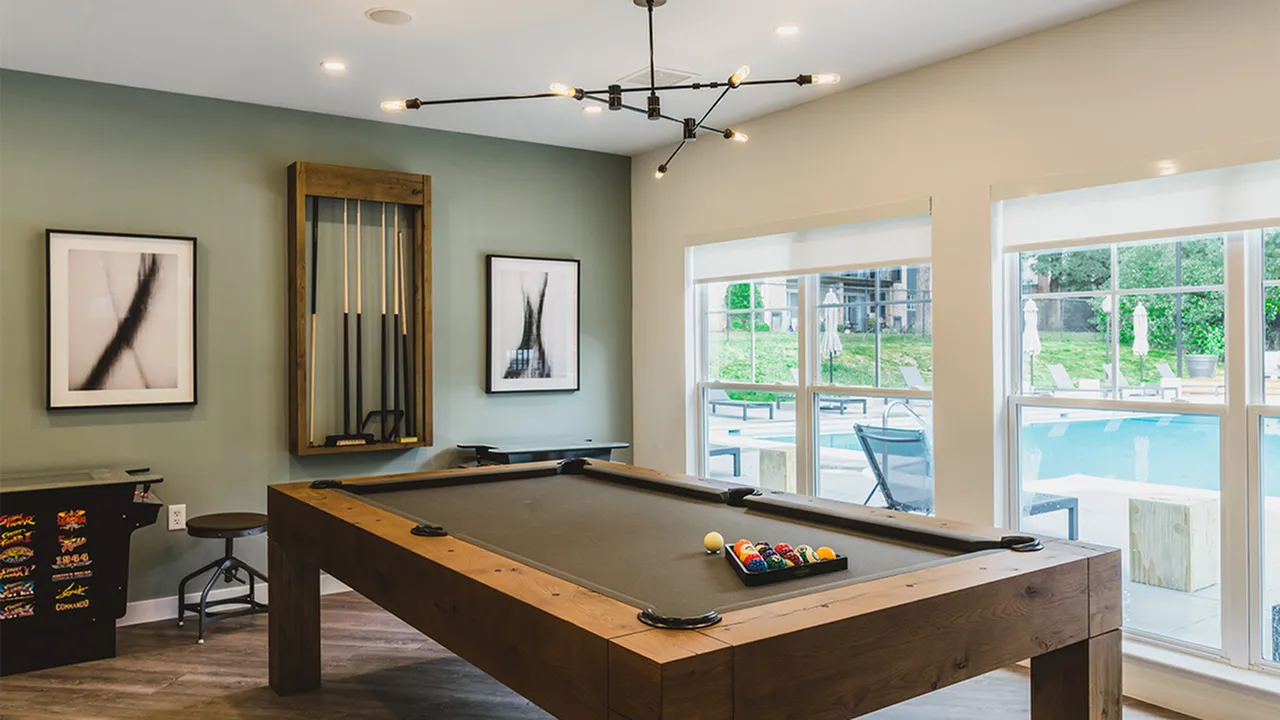 Billiards table and arcade game in clubroom overlooking outdoor pool