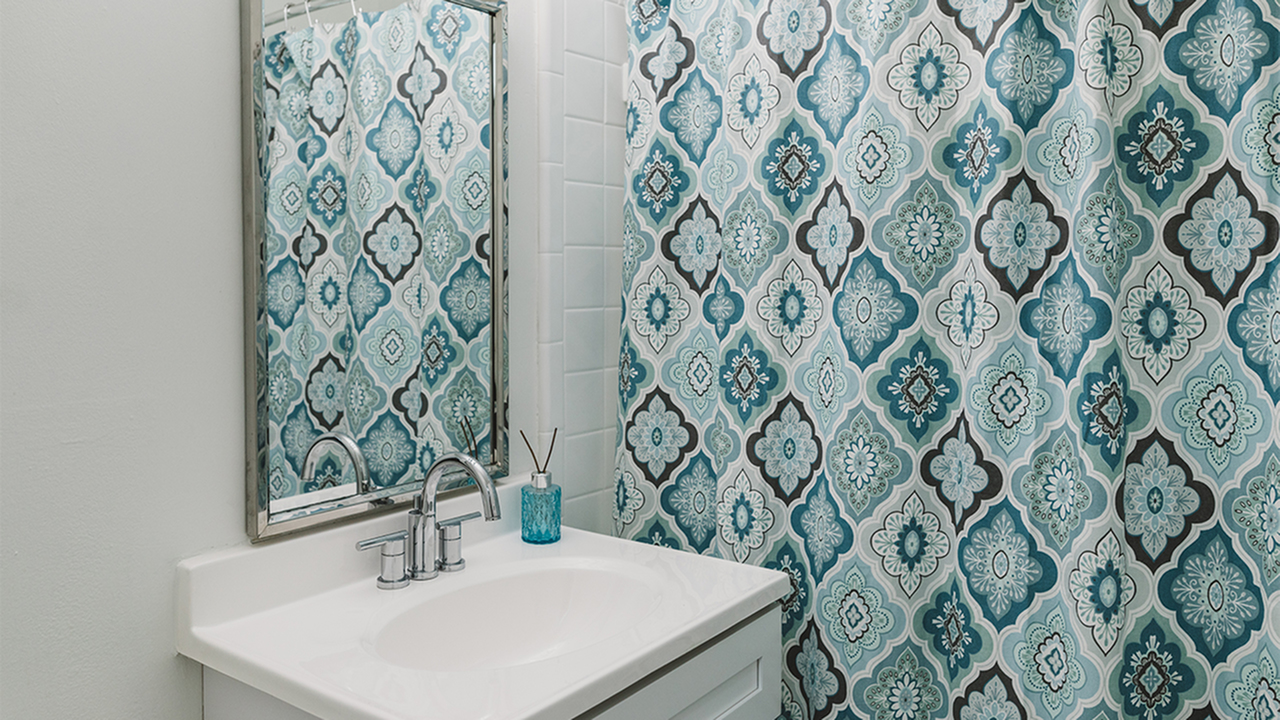 Bathroom sink next to tub with blue patterned shower curtain