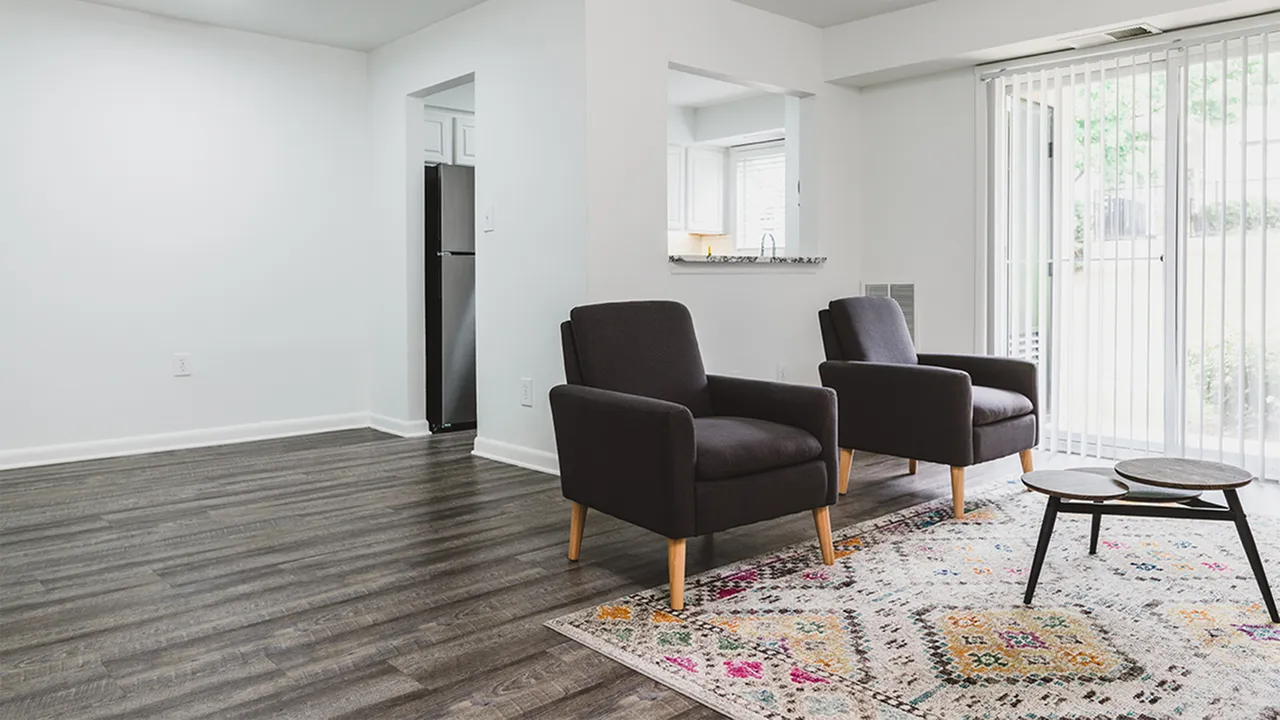 Living area with two brown chairs, patterned rug and plank wood flooring