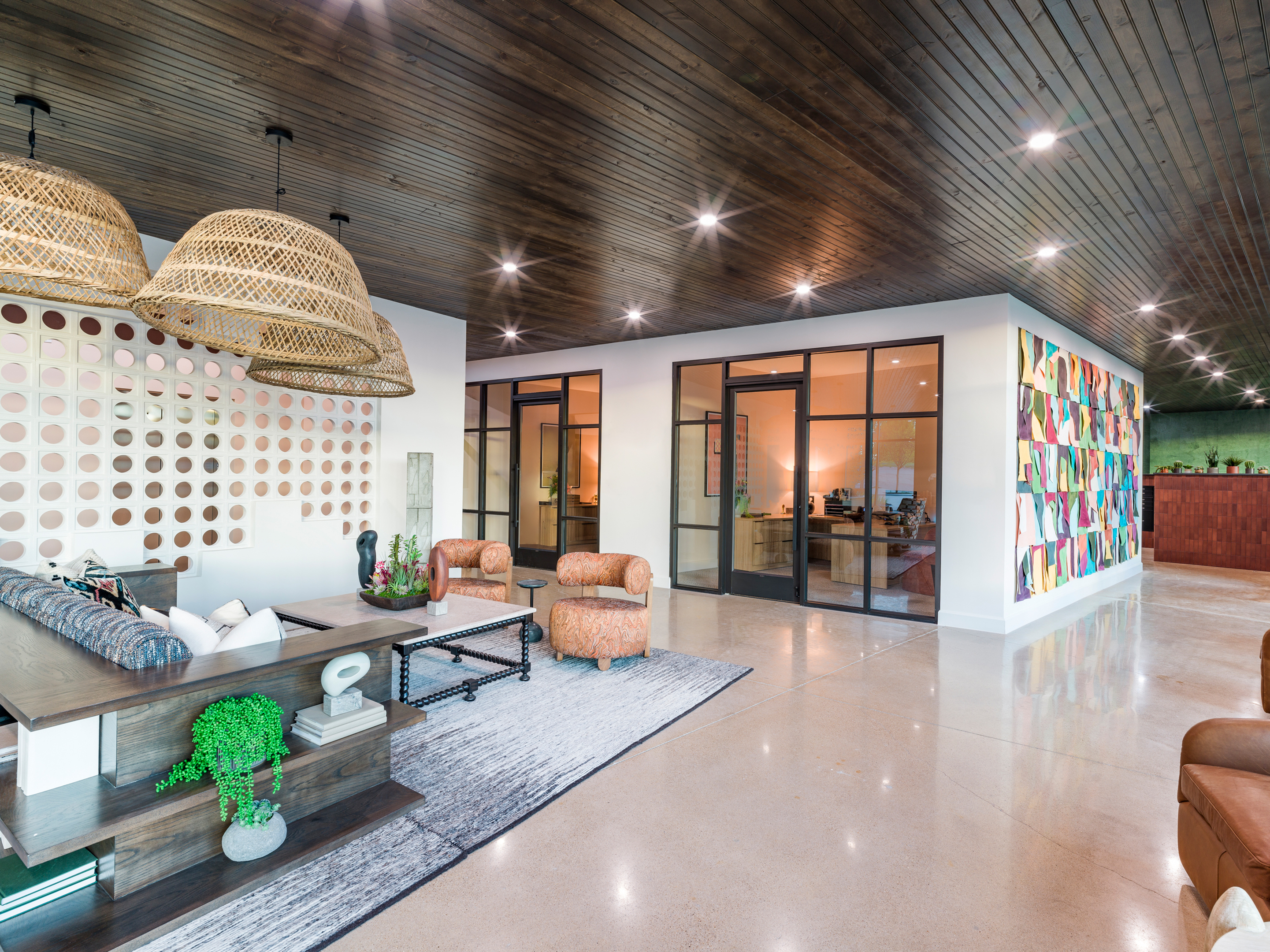 modern clubroom with white walls, light colors tile flooring, moderan dark accents, and comfortable lounging couches and working areas at modera trinity apartments