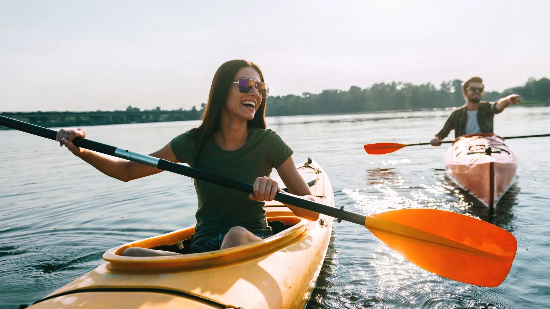 Woman and man rowing in separate kayaks on a lake  Amavi Sherrills Ford