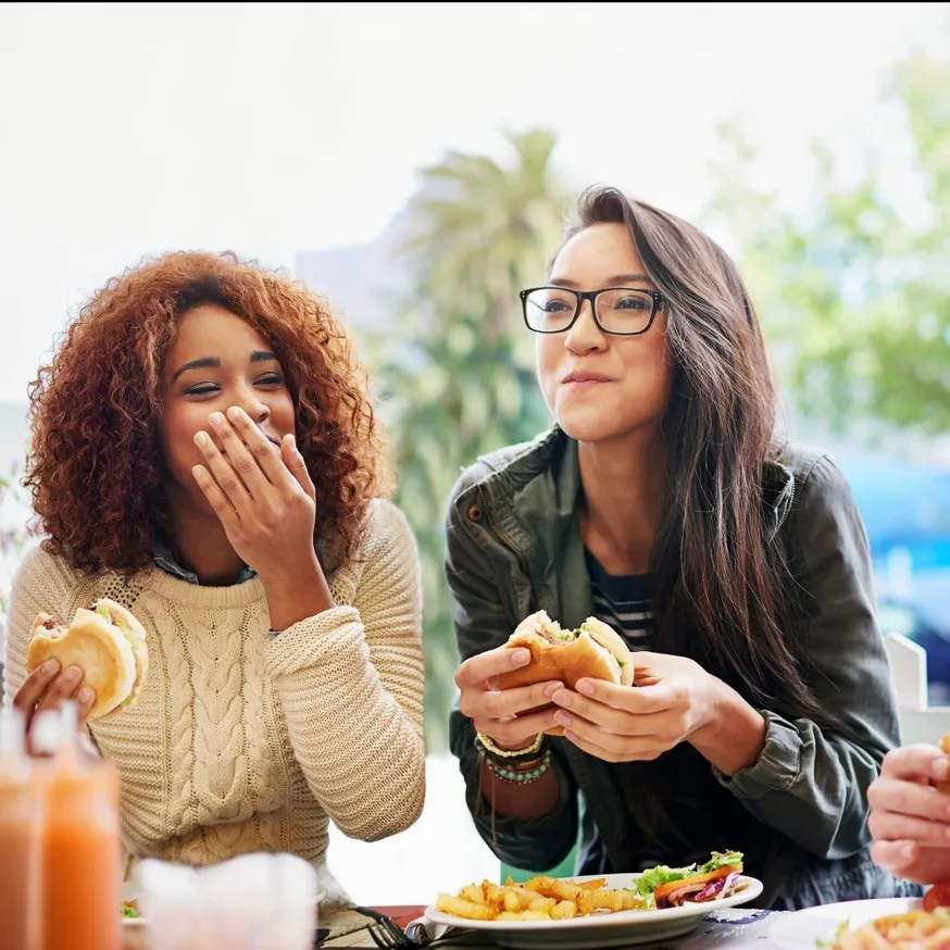2 friends laughing and eating hamburgers