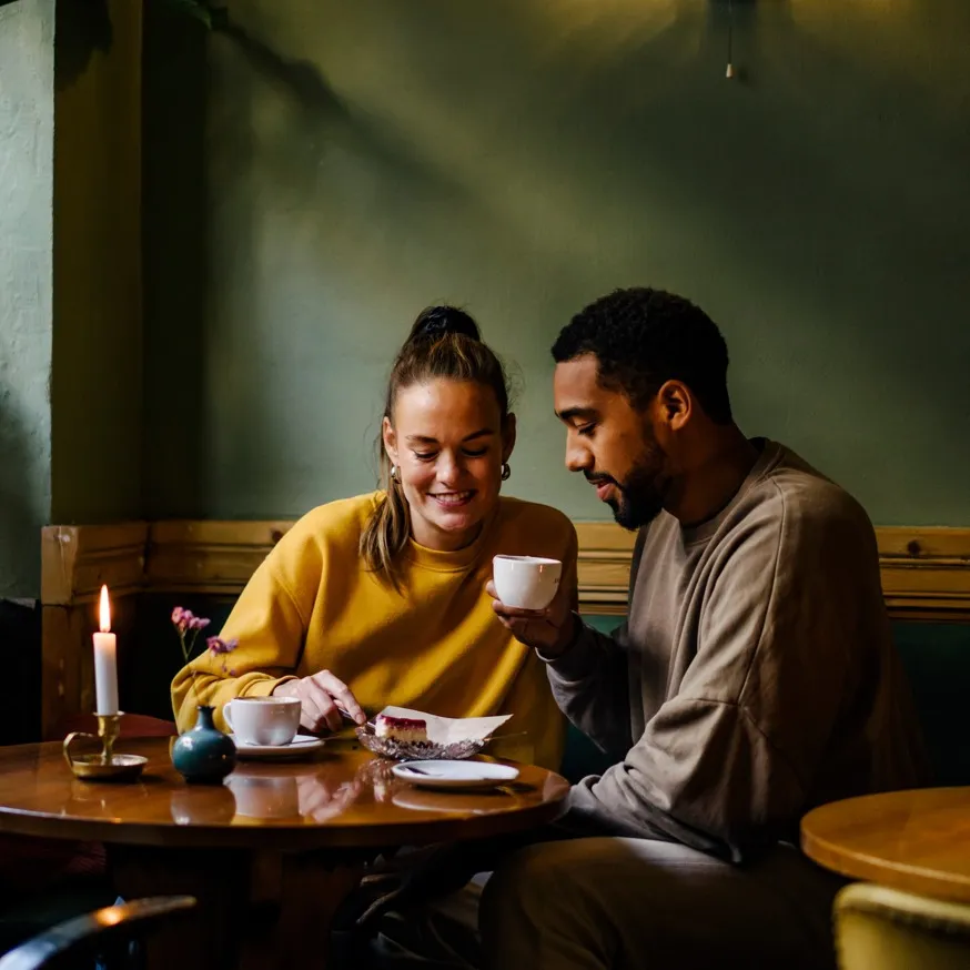 Couple drinking coffee and sharing dessert in cafe