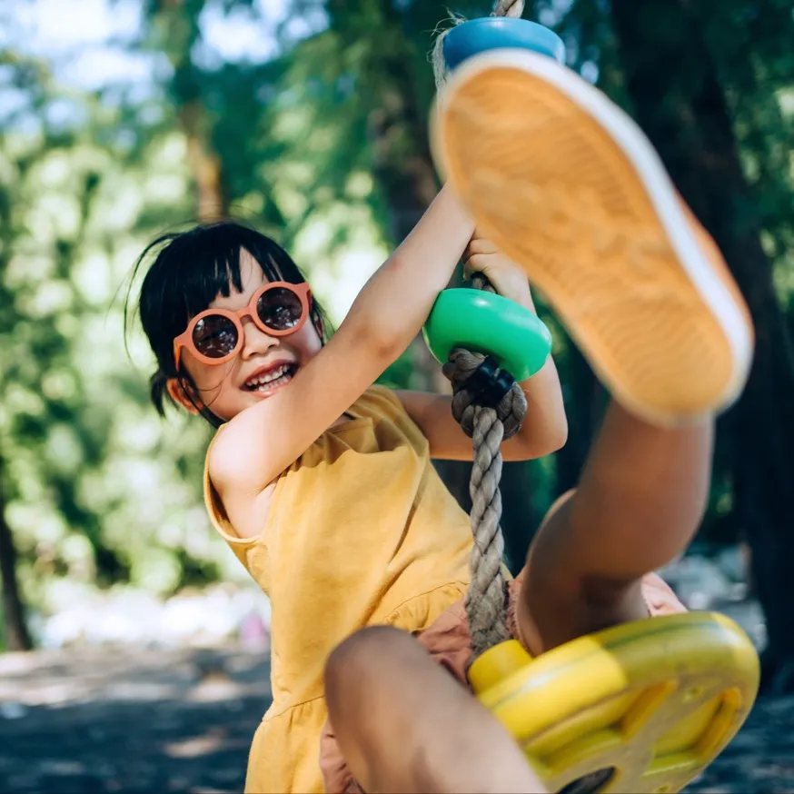 young girl with sunglasses on swinging on a rope