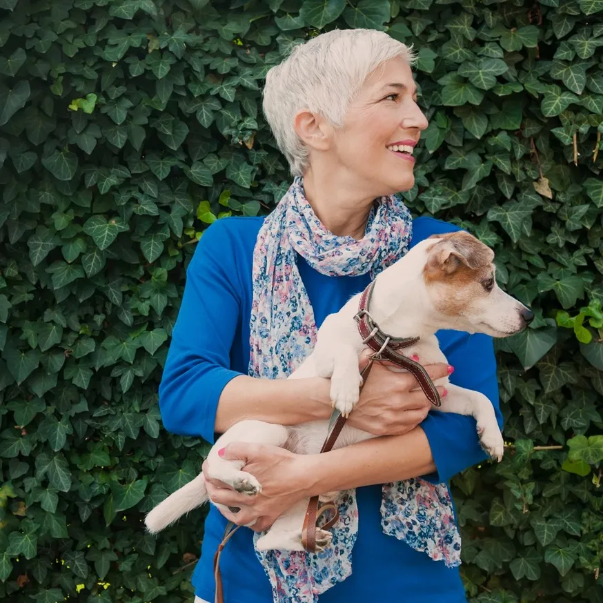 women holding small dog while standing next to a bicycle