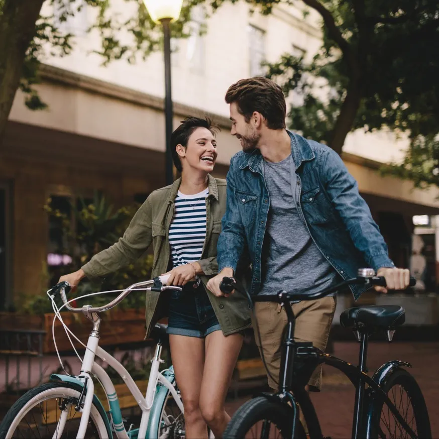 couple walking bikes on street and smiling modera falls church apartment homes for rent in va