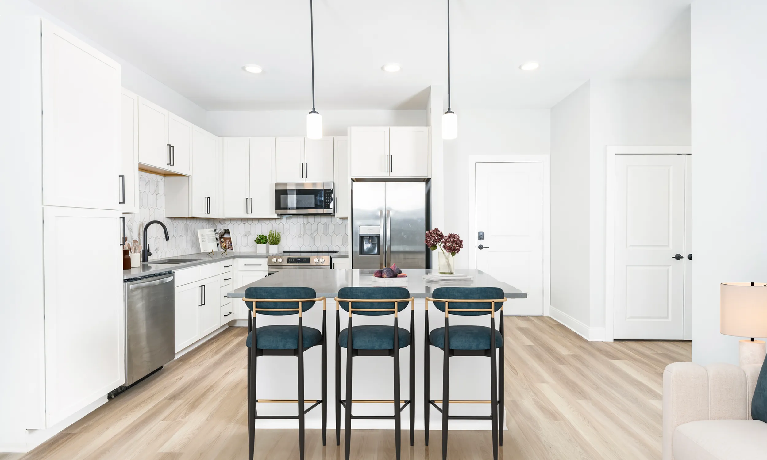 Sleek modern kitchen with white cabinetry, stainless steel appliances, and a stylish island featuring elegant bar stools.